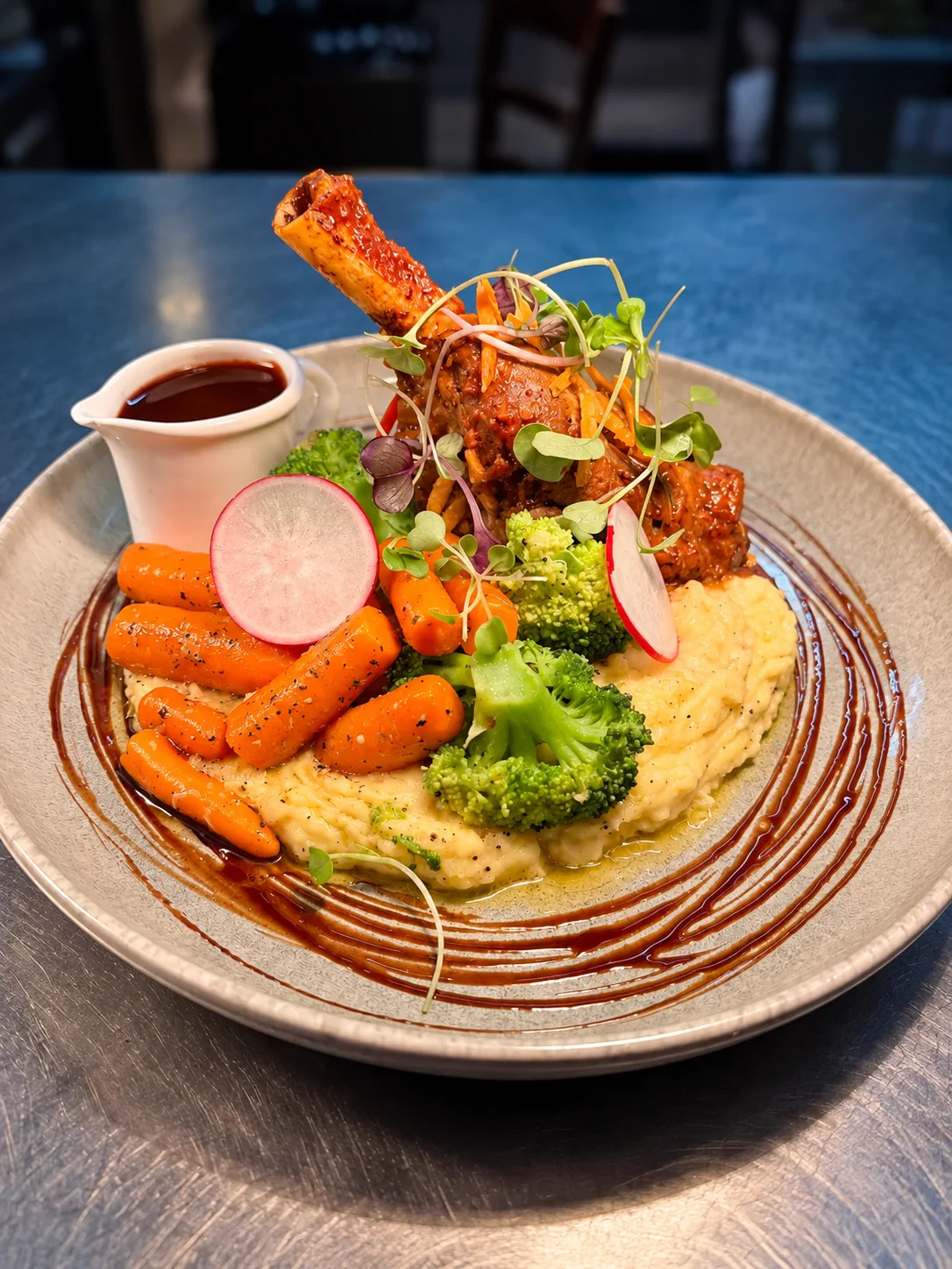 A plated main course with meat, vegetables and mash
